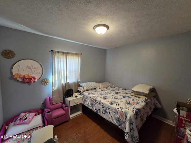 bedroom featuring a textured ceiling, wood finished floors, and baseboards