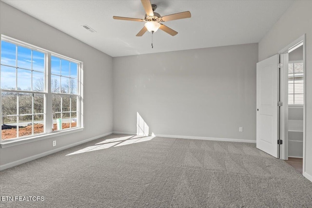 empty room with carpet, visible vents, ceiling fan, and baseboards