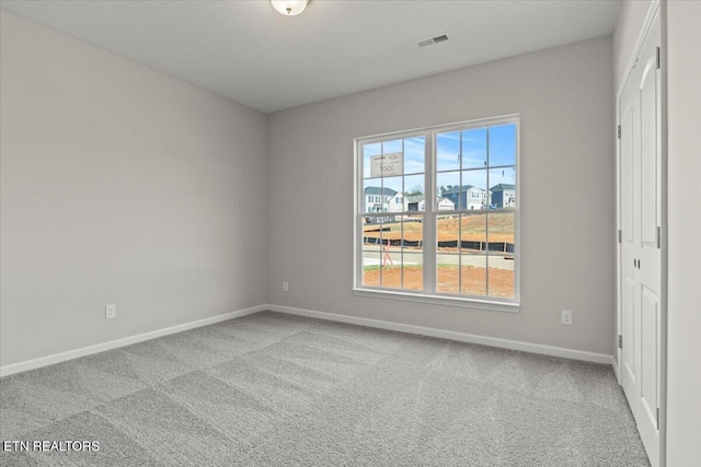 spare room featuring carpet floors, visible vents, and baseboards