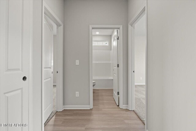 hall featuring light wood-type flooring and baseboards