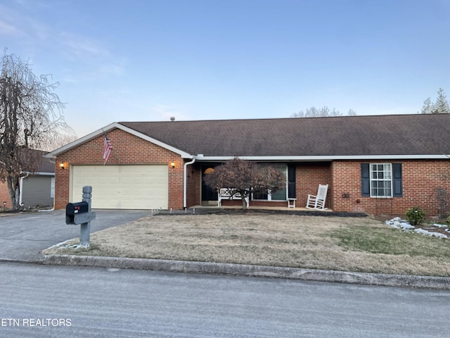 single story home featuring a garage, a front yard, aphalt driveway, and brick siding