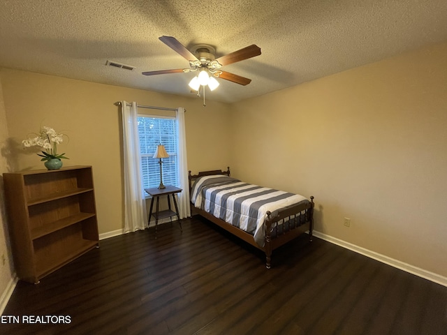 bedroom featuring baseboards, a textured ceiling, visible vents, and wood finished floors