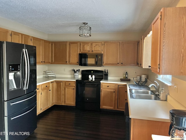 kitchen with dark wood-type flooring, light countertops, a textured ceiling, black appliances, and a sink