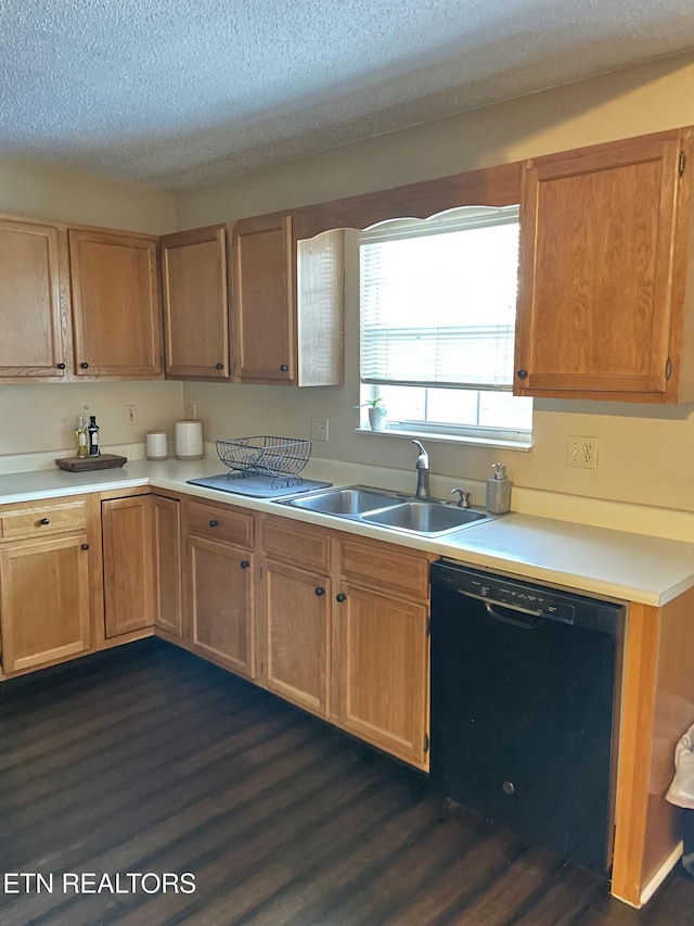 kitchen with a textured ceiling, a sink, black dishwasher, light countertops, and dark wood-style floors