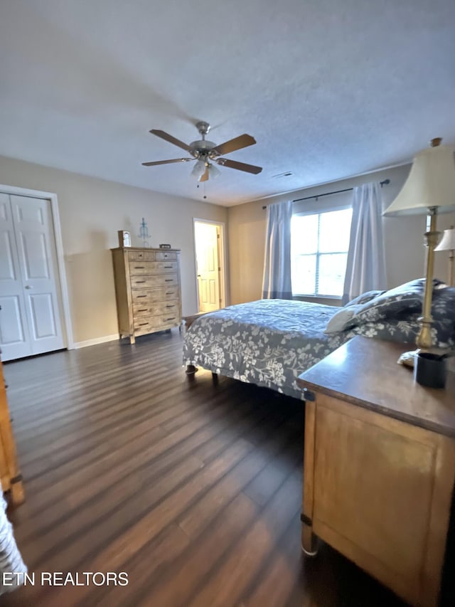 bedroom with dark wood-style floors, a ceiling fan, and baseboards