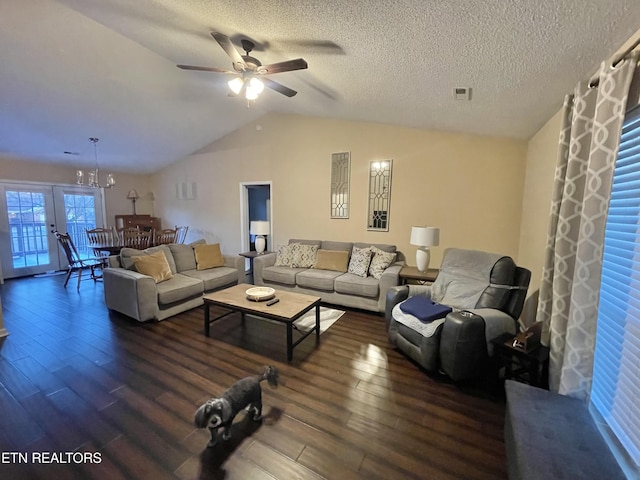 living room with a textured ceiling, ceiling fan with notable chandelier, wood finished floors, visible vents, and vaulted ceiling