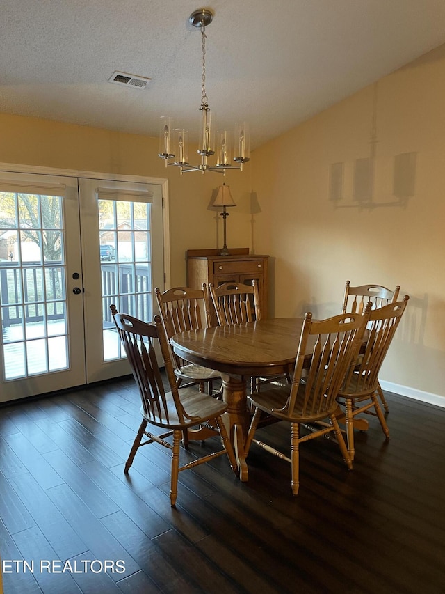 dining area featuring visible vents, wood finished floors, vaulted ceiling, a textured ceiling, and french doors