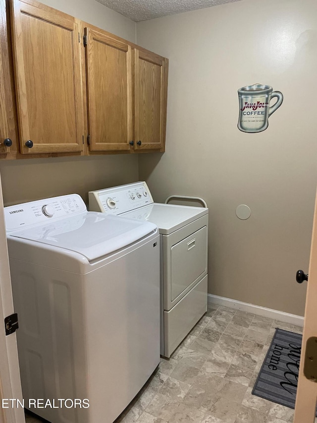 laundry room featuring cabinet space, independent washer and dryer, a textured ceiling, and baseboards