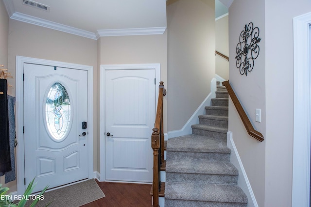 foyer entrance with dark wood-style floors, ornamental molding, visible vents, and baseboards