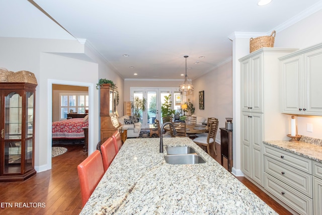 kitchen featuring dark wood-style floors, crown molding, recessed lighting, a sink, and light stone countertops