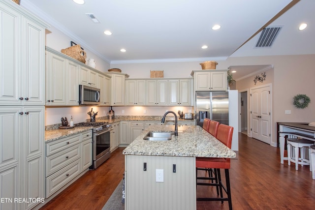 kitchen with appliances with stainless steel finishes, visible vents, a sink, and a breakfast bar area