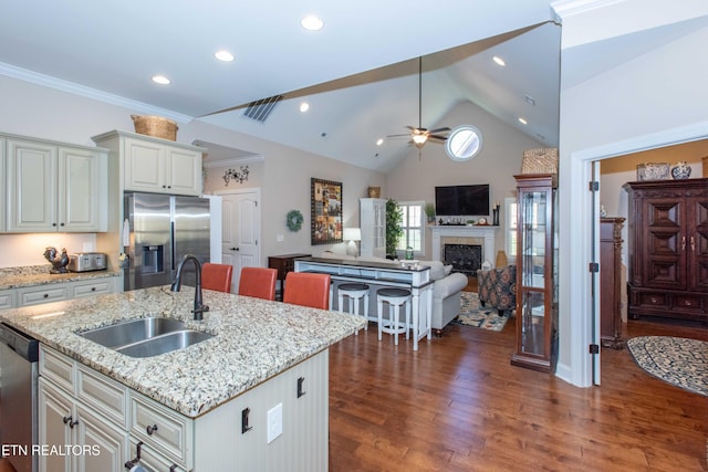 kitchen with a fireplace, a sink, appliances with stainless steel finishes, dark wood-style floors, and an island with sink