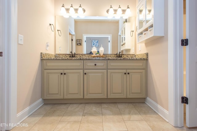 bathroom featuring double vanity, baseboards, and a sink