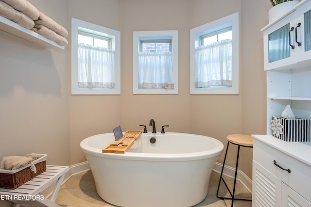 bathroom featuring a soaking tub, baseboards, and tile patterned floors