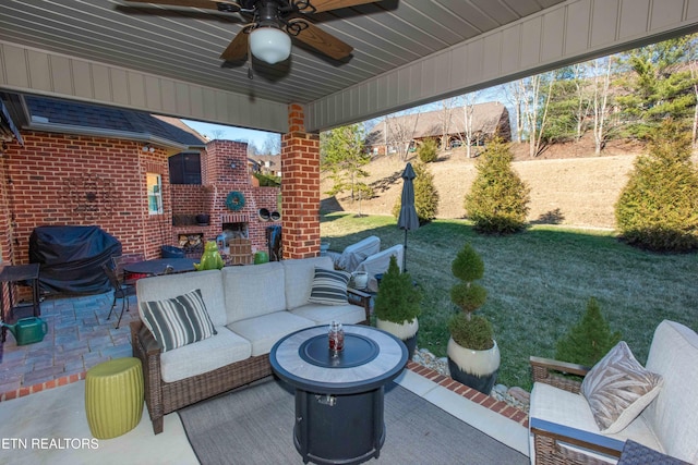 view of patio featuring a ceiling fan and an outdoor living space with a fireplace