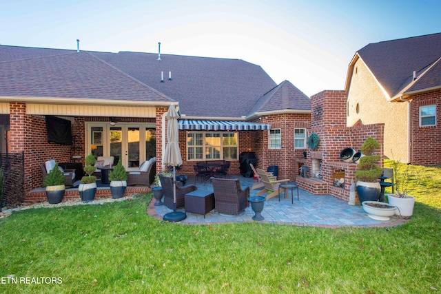 rear view of house featuring french doors, brick siding, a yard, roof with shingles, and a patio area