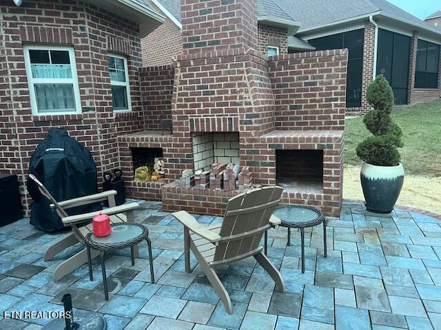 view of patio / terrace with an outdoor brick fireplace and area for grilling