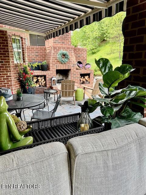 balcony with an outdoor brick fireplace and a patio