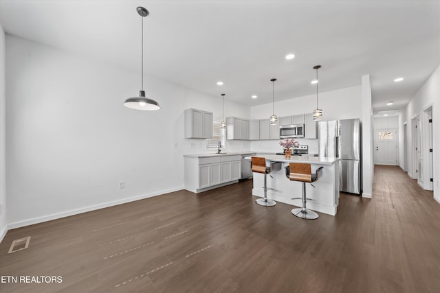 kitchen featuring a breakfast bar area, dark wood-style flooring, visible vents, light countertops, and appliances with stainless steel finishes