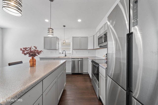 kitchen with dark wood-style floors, hanging light fixtures, stainless steel appliances, a sink, and recessed lighting