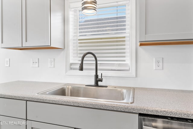 room details featuring stainless steel dishwasher, light countertops, and a sink