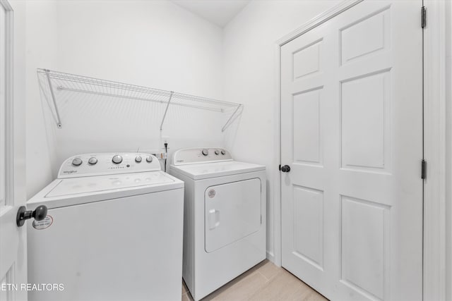 clothes washing area with light wood-style floors, laundry area, and washing machine and clothes dryer