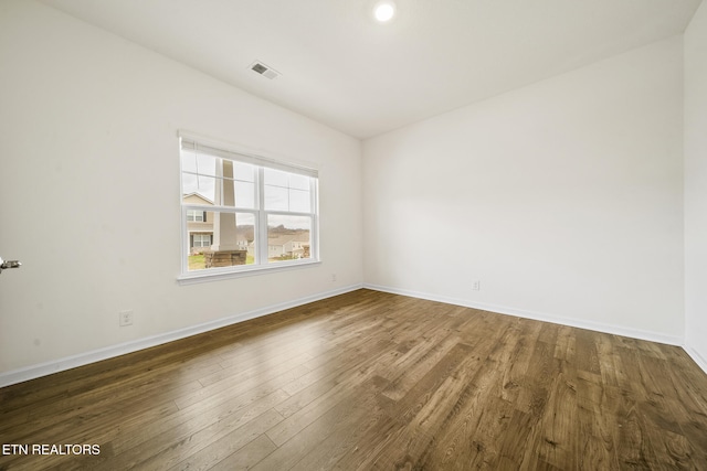 empty room featuring lofted ceiling, baseboards, visible vents, and wood finished floors