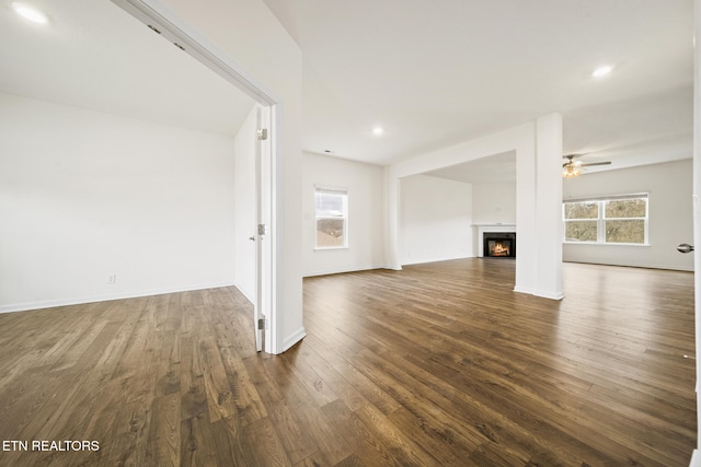 unfurnished living room with baseboards, a ceiling fan, dark wood-type flooring, a lit fireplace, and recessed lighting