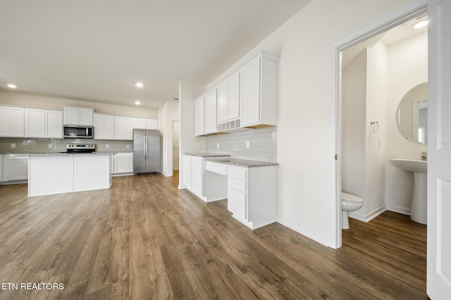 kitchen with stainless steel appliances, wood finished floors, and white cabinetry