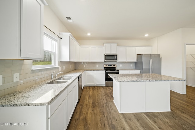 kitchen with stainless steel appliances, a kitchen island, a sink, visible vents, and white cabinetry