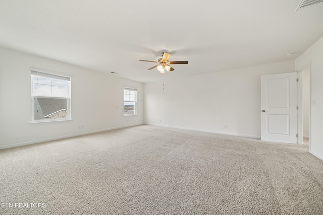 carpeted empty room with baseboards, visible vents, and ceiling fan