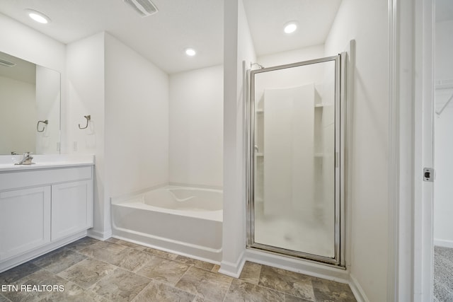 bathroom with vanity, visible vents, baseboards, a bath, and a stall shower