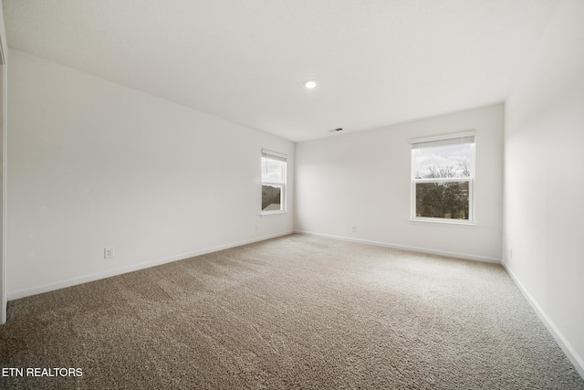 unfurnished room with carpet floors, visible vents, and baseboards