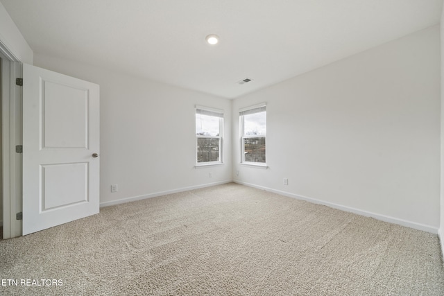 carpeted spare room featuring visible vents and baseboards