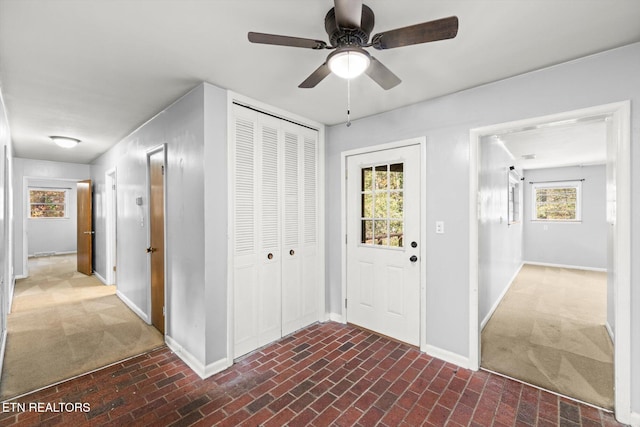 foyer entrance featuring brick floor, ceiling fan, and baseboards