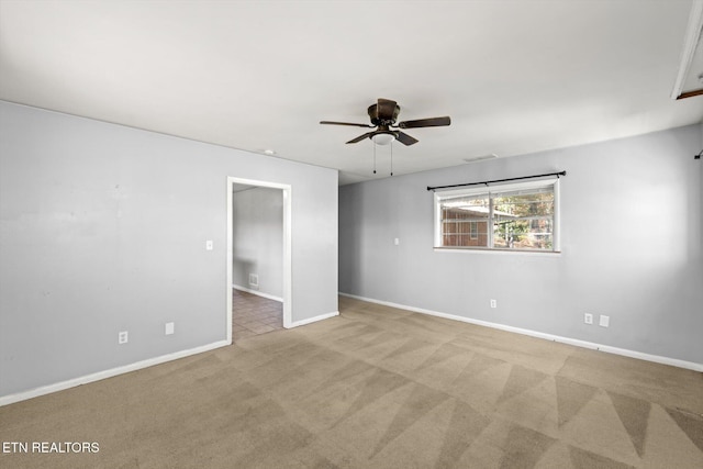 carpeted empty room with a ceiling fan and baseboards