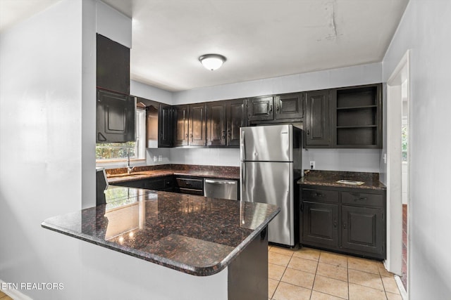 kitchen featuring dark stone counters, appliances with stainless steel finishes, a peninsula, open shelves, and a sink