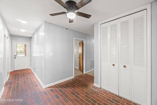 corridor with brick floor, visible vents, and baseboards