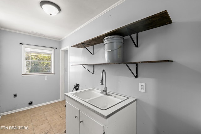 clothes washing area with hookup for an electric dryer, a sink, baseboards, cabinet space, and crown molding