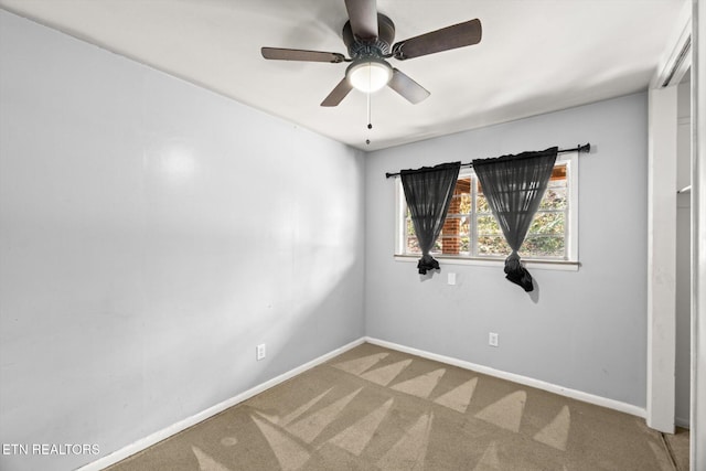 carpeted spare room with baseboards and a ceiling fan