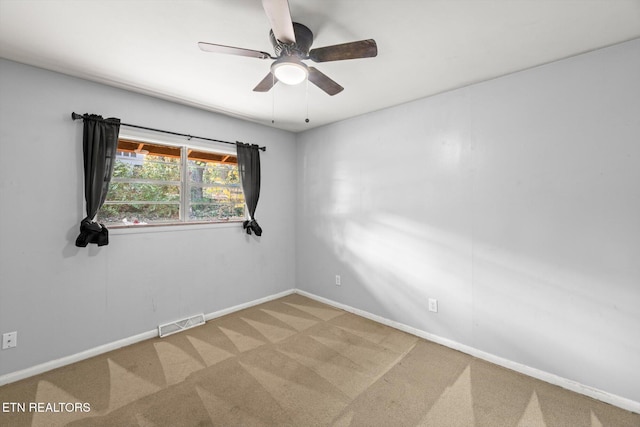 carpeted spare room featuring a ceiling fan, visible vents, and baseboards