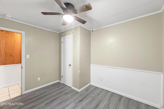 spare room with wainscoting, crown molding, and wood finished floors