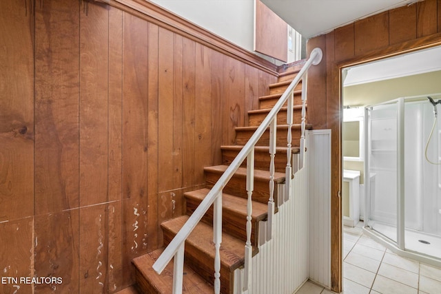 stairs featuring tile patterned flooring and wood walls