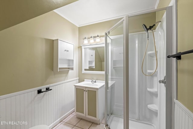 bathroom with tile patterned flooring, vanity, wainscoting, a shower stall, and crown molding