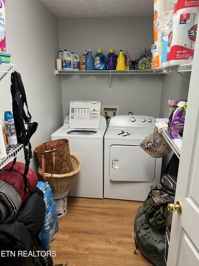 laundry area with laundry area, light wood-style flooring, a textured ceiling, and independent washer and dryer