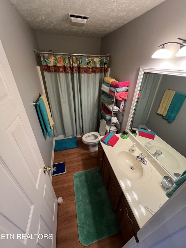 full bathroom featuring a textured ceiling, toilet, wood finished floors, vanity, and a shower with curtain