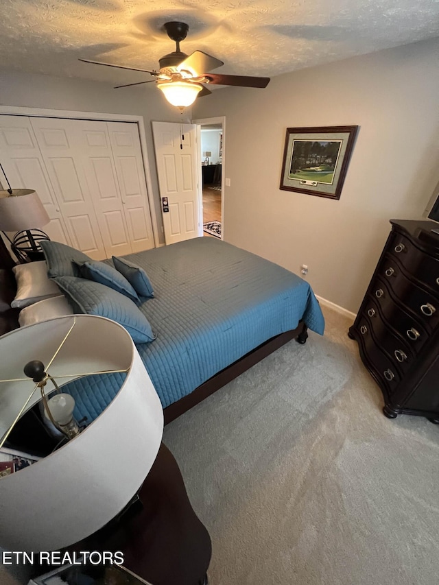 bedroom featuring baseboards, a ceiling fan, carpet, a textured ceiling, and a closet