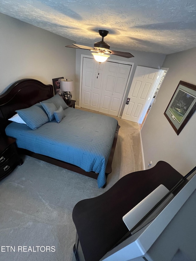 bedroom with a textured ceiling, a closet, carpet, and a ceiling fan