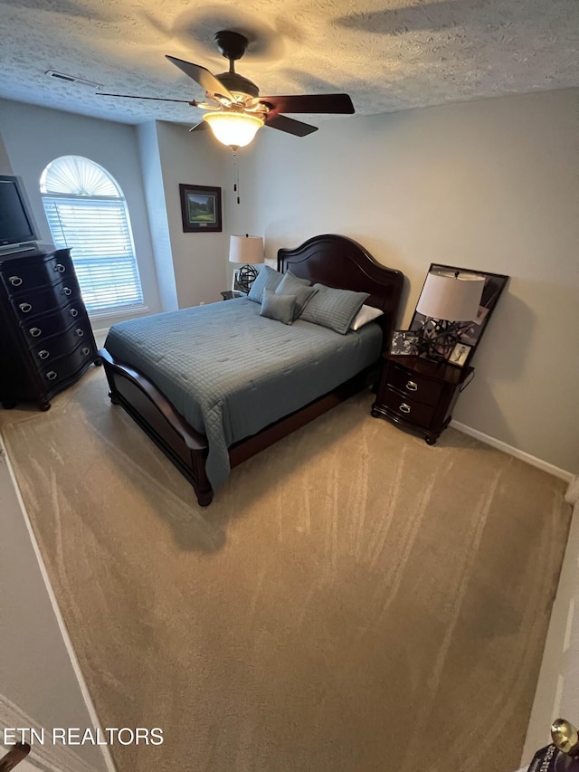 bedroom featuring a ceiling fan, light colored carpet, a textured ceiling, and baseboards