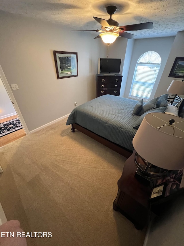 bedroom featuring carpet floors, a textured ceiling, baseboards, and a ceiling fan